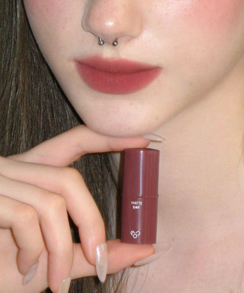 AOU Matte Bar de la marque AOU, rouge mat, sur lèvres, contexte maquillage en gros plan, sur peau claire