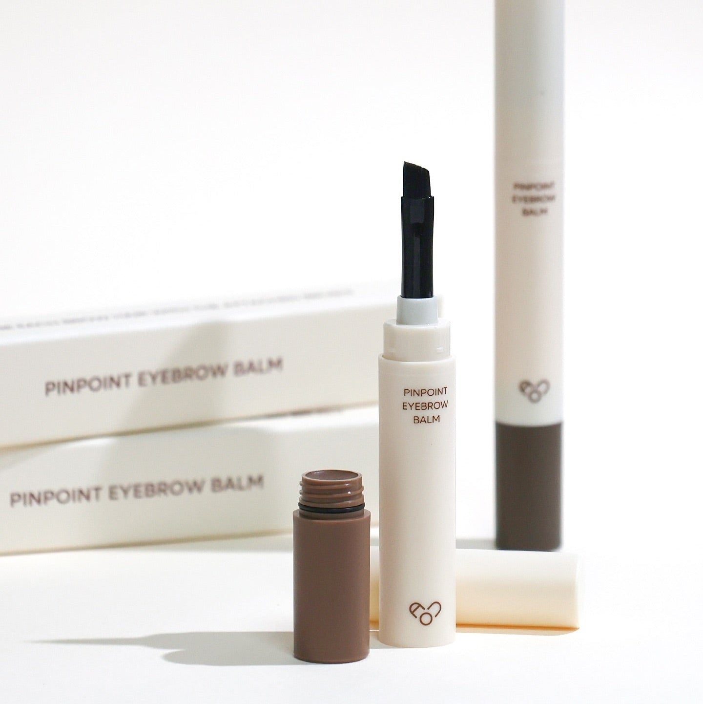 AOU Pinpoint Eyebrow Balm de la marque AOU, produit maquillage sourcils sur fond blanc, packaging et tube au premier plan.