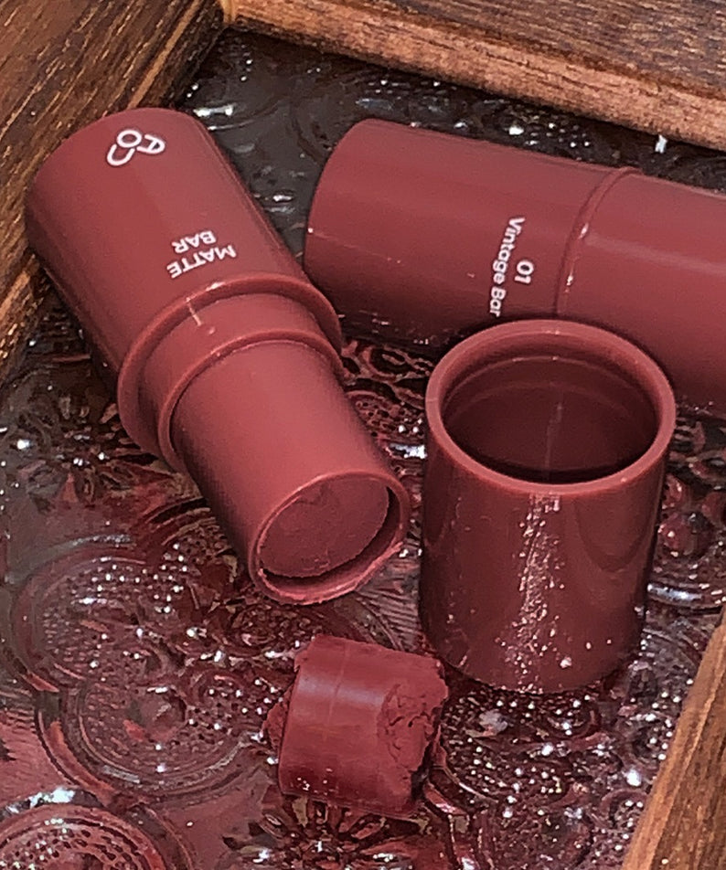 AOU Matte Bar en teinte terres rouges sur un plateau en bois, esthétique et chic, parfait pour une finition matte élégante.