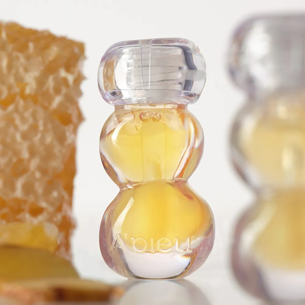 A'PIEU Jelly Honey Lip Oil 4g, branding en français sur flacon gouttes miel, gros plan décor miel, fond clair
