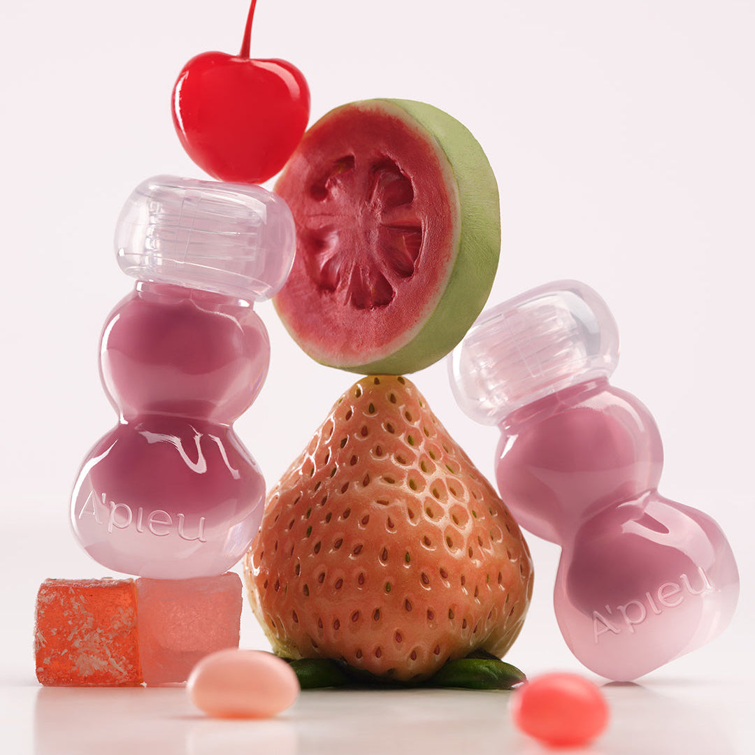 A'PIEU Jelly Tint (10 Colors) de la marque A'PIEU, maquillage illustré sur des fruits et des tubes roses en studio