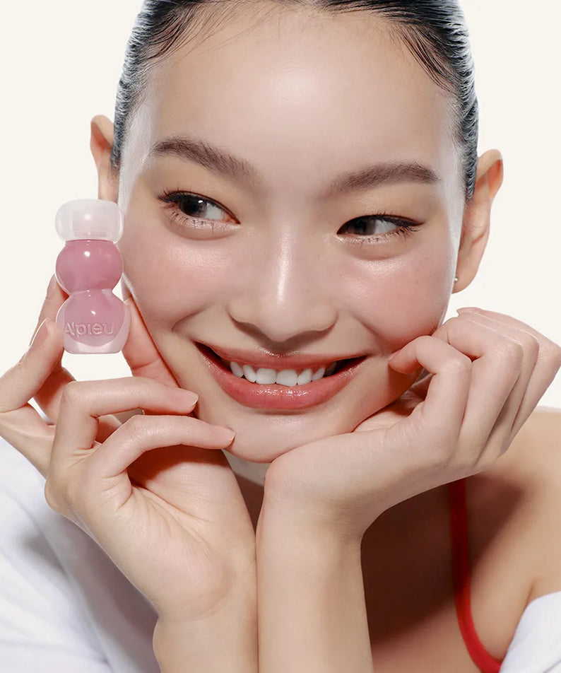 A'PIEU Jelly Tint (10 Colors) : la teinte jelly sur un visuel beauté, une femme souriante tenant le produit