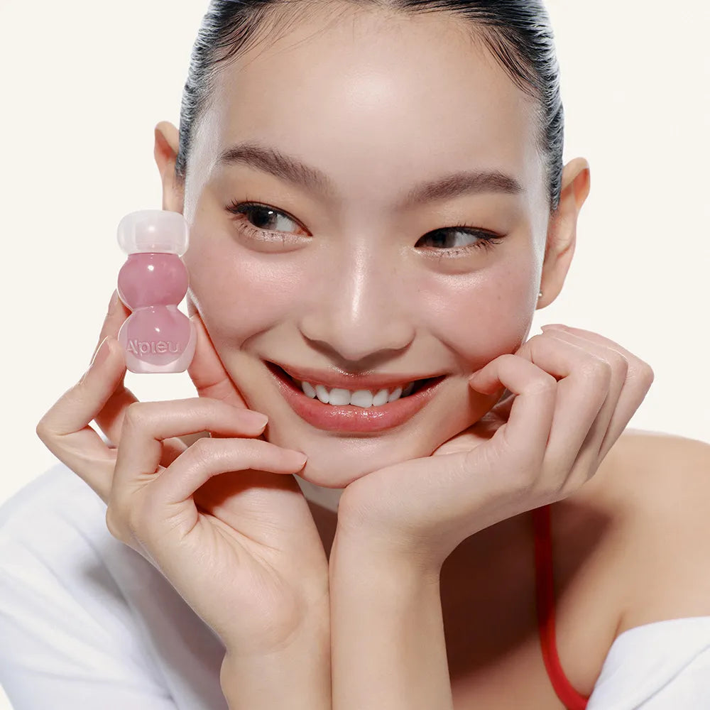 A'PIEU Jelly Tint (10 Colors) : la teinte jelly sur un visuel beauté, une femme souriante tenant le produit