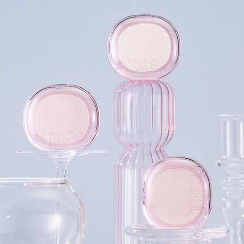 A'PIEU Juicy Pang Glimmering Highlighter, marque A'PIEU, flacon rose maquillage sur fond clair et flacons transparents.