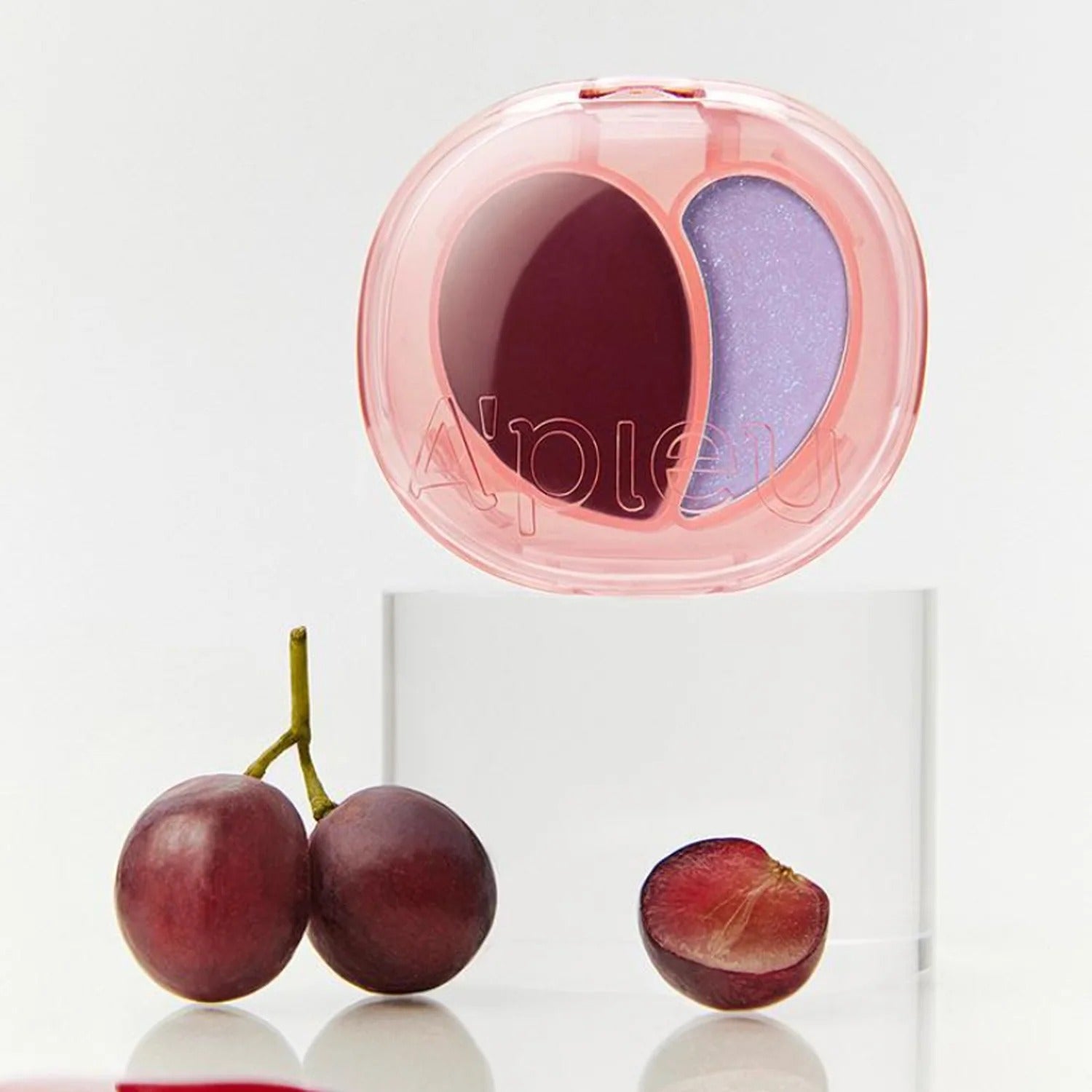 A'PIEU Juicy Pang Mood Blending Lip & Cheek Balm, packaging rose et duo de teintes sur fond blanc, raisins et prune.