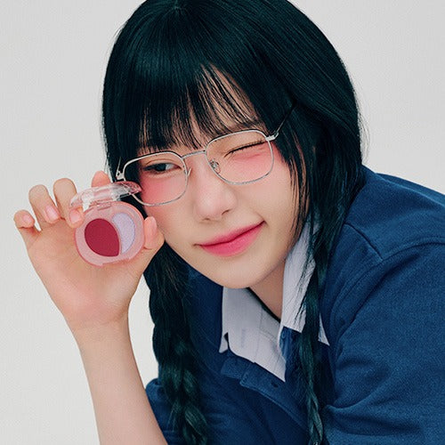 A'PIEU Juicy Pang Mood Blending Lip & Cheek Balm sur fond clair, fille aux lunettes avec pot rose, visuel beauté
