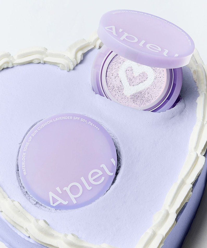 Décris l’image en français : A'PIEU Waterlock Tone-Up Sun Cushion Lavender 15g, coussin hydratant lavande, boîte ouverte sur fond clair.