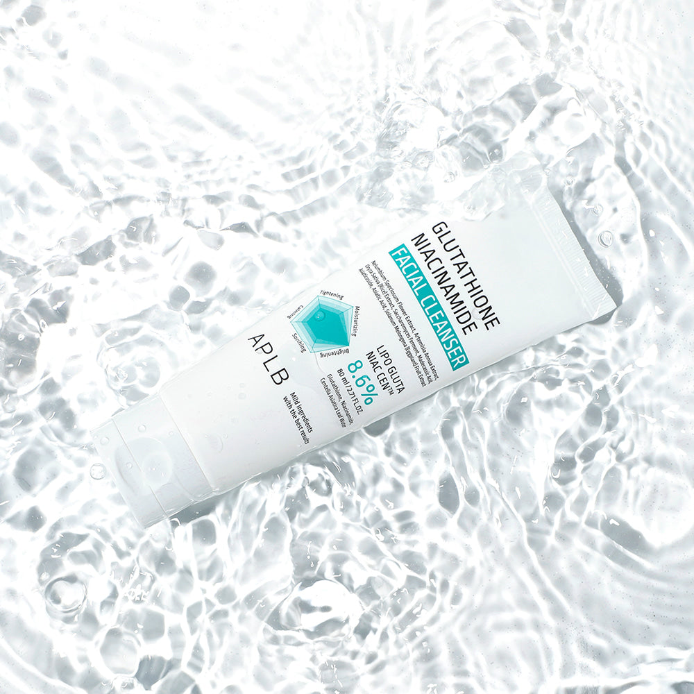Décris l'image en français : APLB Glutathione Niacinamide Facial Cleanser 80ml sur tissu bulles, marque APLB, flacon blanc.