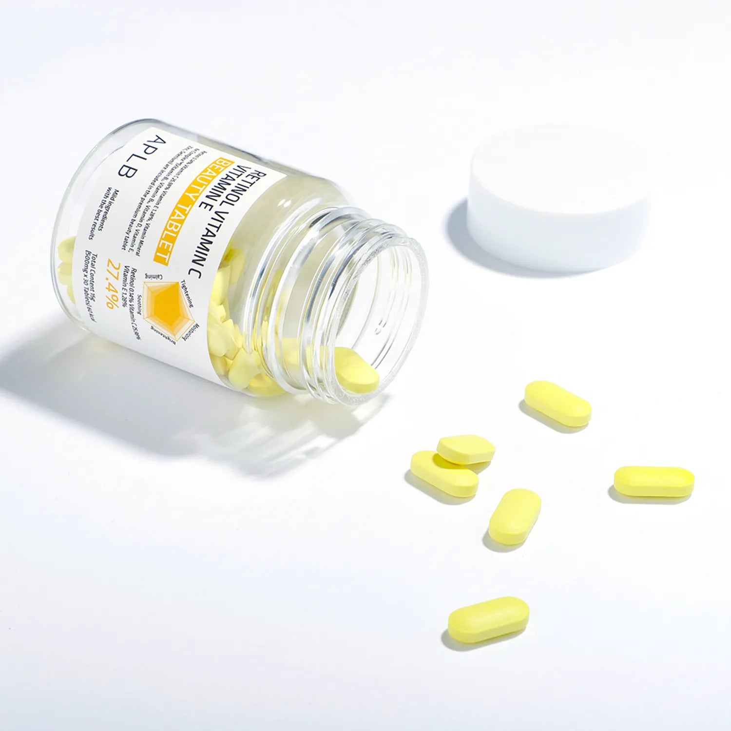 APLb Retinol Vitamin C Vitamin E Beauty Tablet APLB, comprimés jaunes sur fond blanc, flacon posé avec poudrier blanc