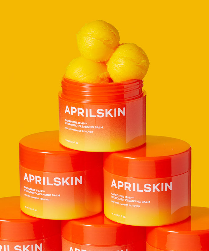 APRILSKIN Carotene Melting Cleansing Balm empilés sur fond orange.
