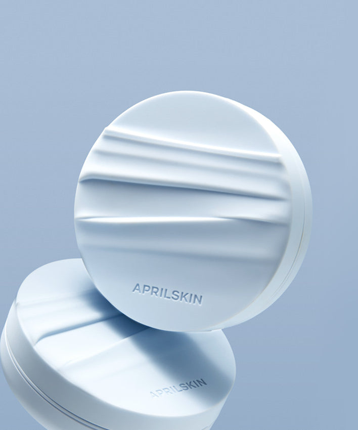 APRILSKIN Glowing Matt Cushion + Refill sur fond bleu élégant, idéal pour un teint lumineux et mat.