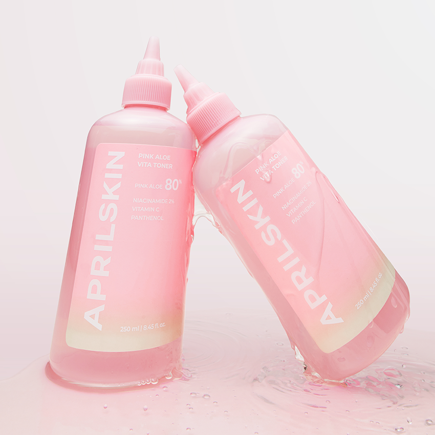 APRILSKIN Pink Aloe Vita Toner, bouteille rose de la marque APRILSKIN sur fond clair avec éclaboussures d’eau