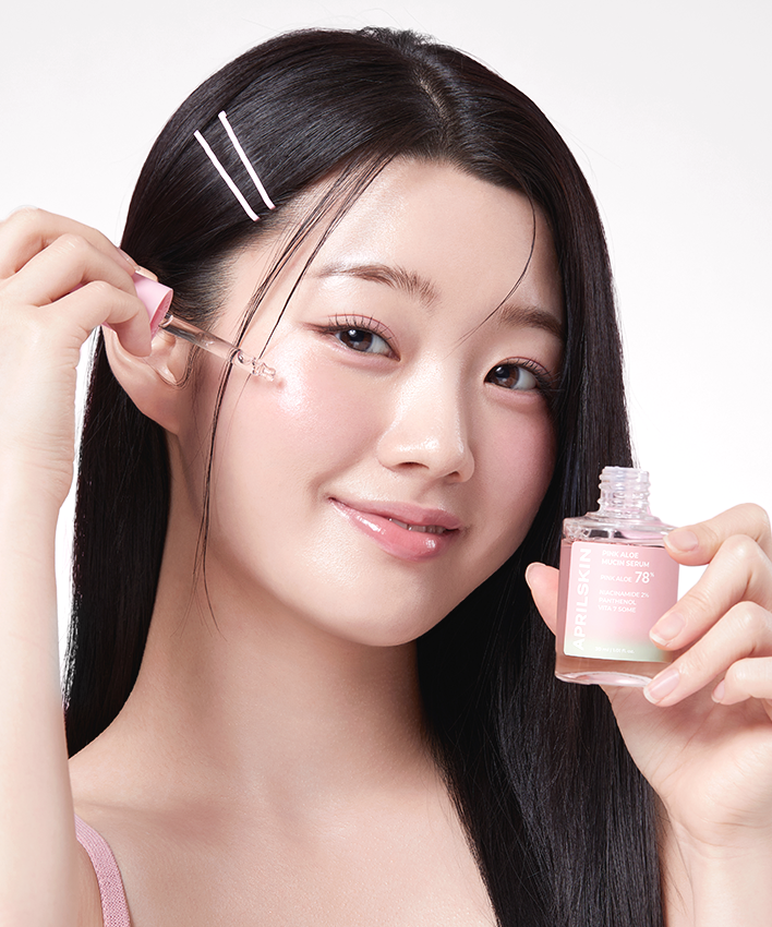 APRILSKIN Pink Aloe Mucin Serum de la marque APRILSKIN : flacon rose et sérum sur peau, femme beauté en gros plan
