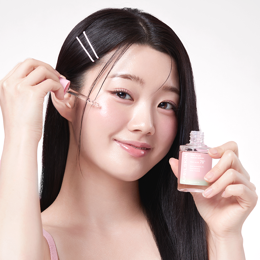 APRILSKIN Pink Aloe Mucin Serum de la marque APRILSKIN : flacon rose et sérum sur peau, femme beauté en gros plan