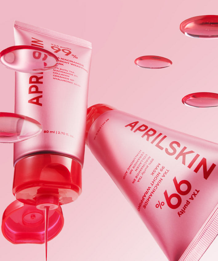 APRILSKIN TXA Niacinamide 99 Night Wrapping Mask 80ml en tubes sur fond rose avec gouttes de sérum.