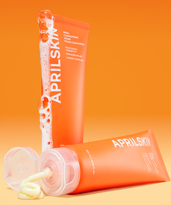 APRILSKIN Real Carrotene Acne Foam Cleanser 120ml d’APRILSKIN, flacon rose/orange, mousse sur fond orange lumineux.