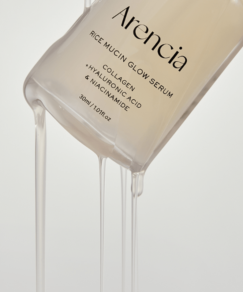 Flacon de sérum éclatant ARENCIA Rice Mucin Glow Serum 30ml, textures huileuses coulant sur le côté, contenant du collagène.