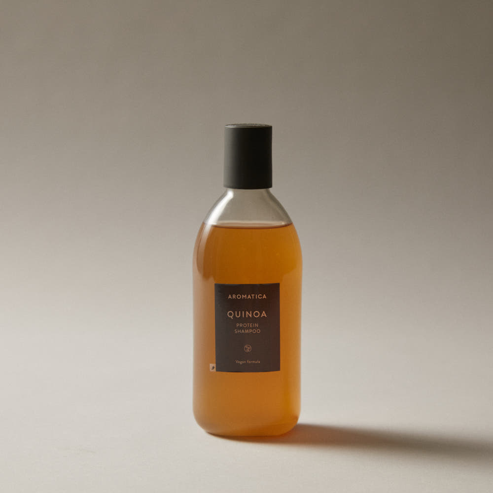 Décris l'image en français en mentionnant le produit, la marque et le contexte visuel: AROMATICA Quinoa Protein Shampoo 400ml, flacon sur fond clair.