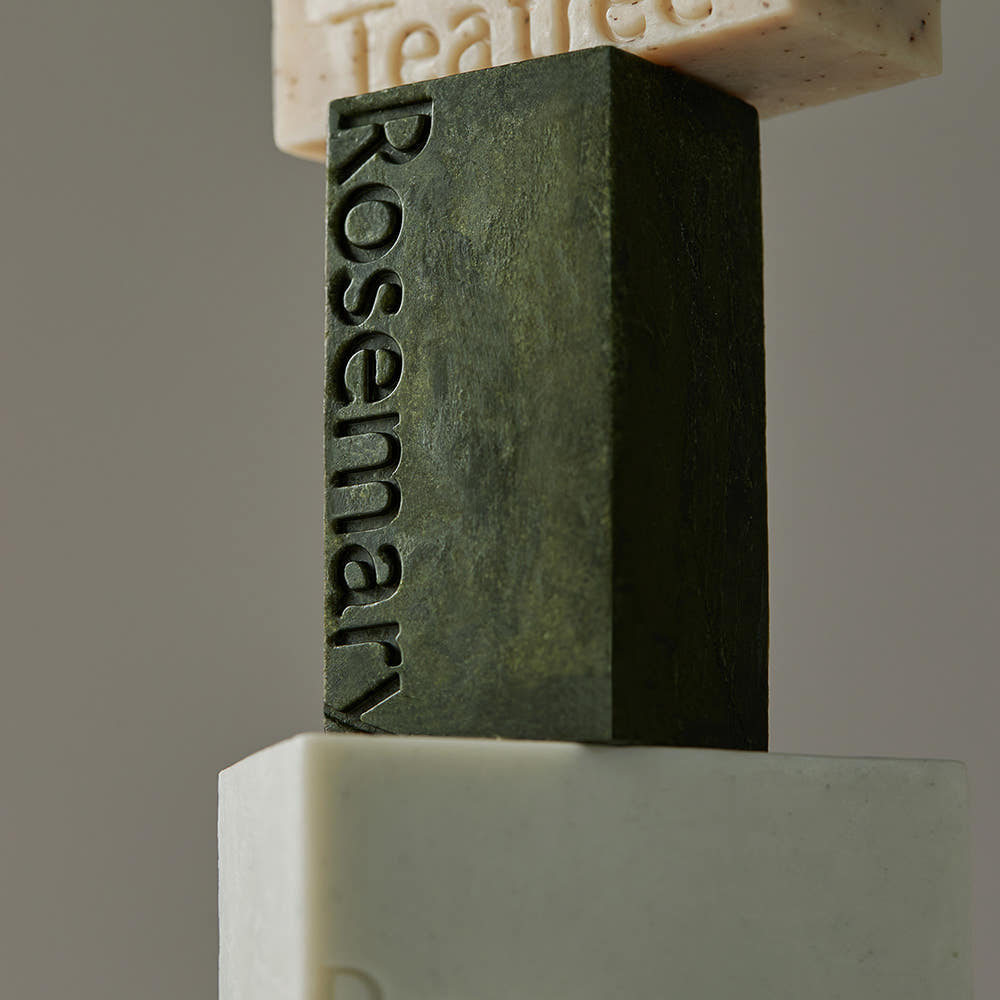AROMATICA Rosemary Scalp Scaling Shampoo Bar 135g, savon shampooing à la romarin, marque Roti sur bloc vert en studio.