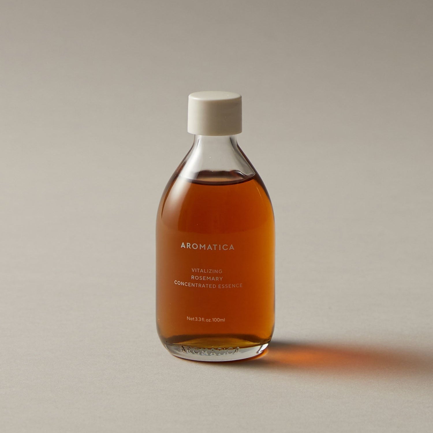 AROMATICA Vitalizing Rosemary Concentrated Essence 200ml, bouteille ambrée sur fond clair, essence à la main, style photo produit