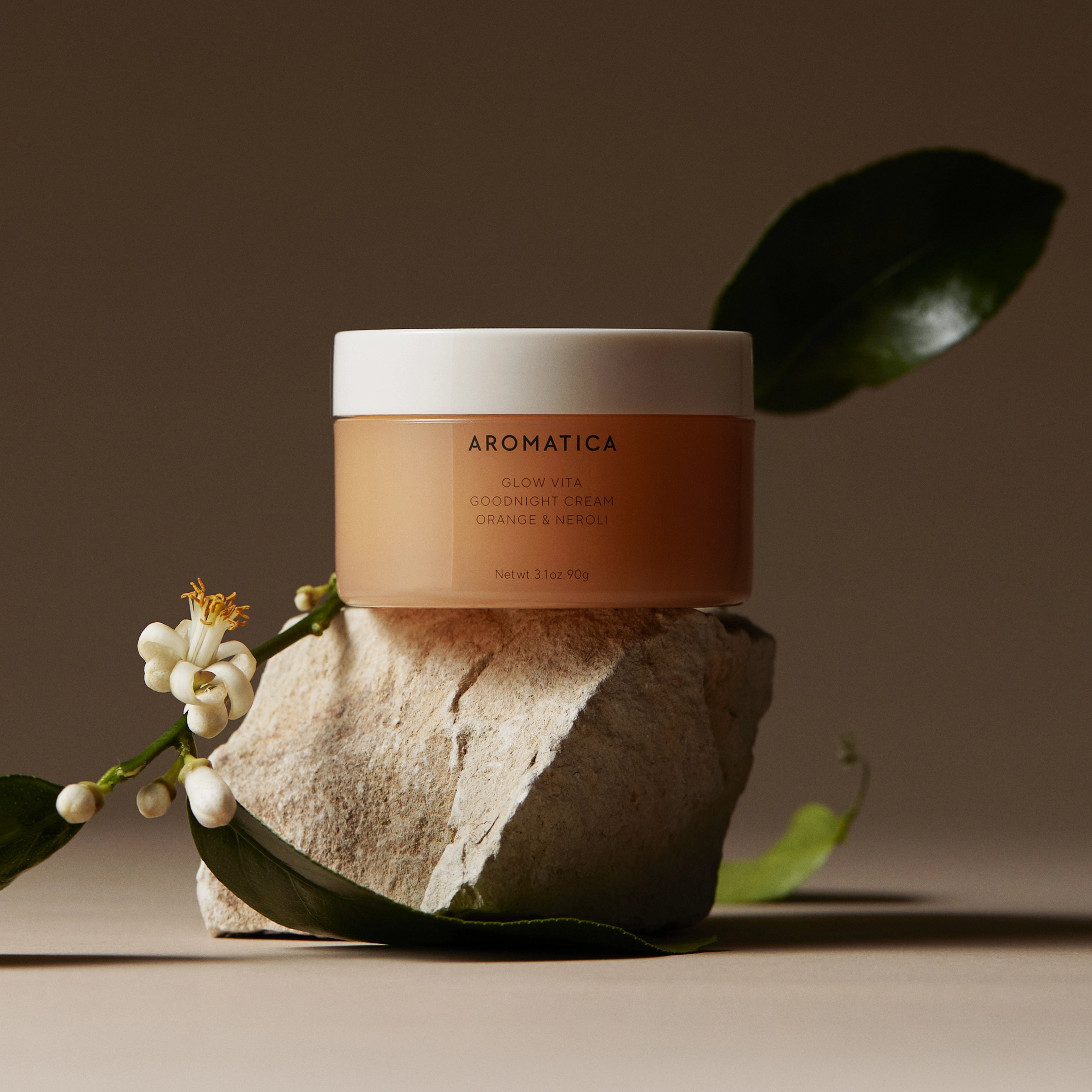 AROMATICA Glow Vita Good Night Cream Orange & Neroli 90G, crème de nuit sur fond beige avec feuille et fleur, marque AROMATICA.