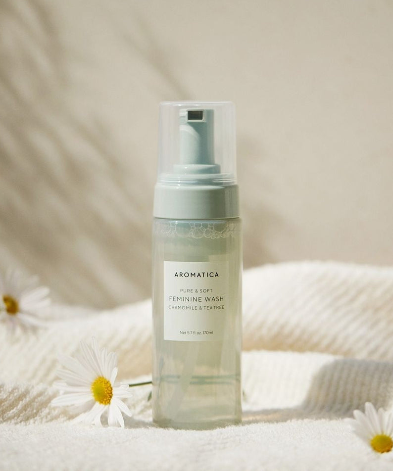 AROMATICA Pure & Soft Chamomile & Tea Tree Feminine Wash 170ml, flacon sur serviette, fleurs, dégradé clair, marque AROMATICA