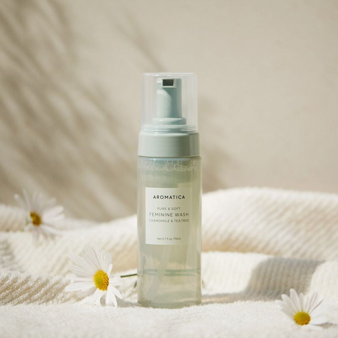 AROMATICA Pure & Soft Chamomile & Tea Tree Feminine Wash 170ml, flacon sur serviette, fleurs, dégradé clair, marque AROMATICA