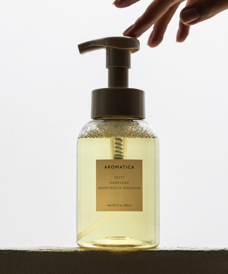 AROMATICA Zesty Hand Soap Grapefruit & Tangerine 300ML, main distribuant du savon, bouteille transparente sur fond clair