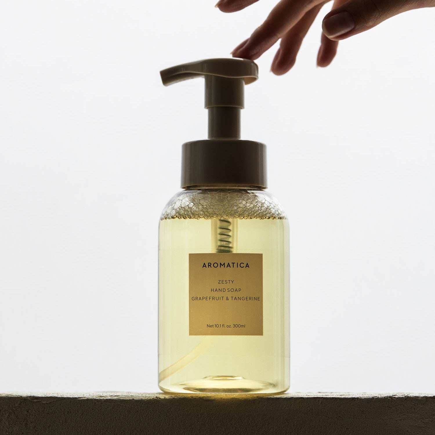 AROMATICA Zesty Hand Soap Grapefruit & Tangerine 300ML, main distribuant du savon, bouteille transparente sur fond clair