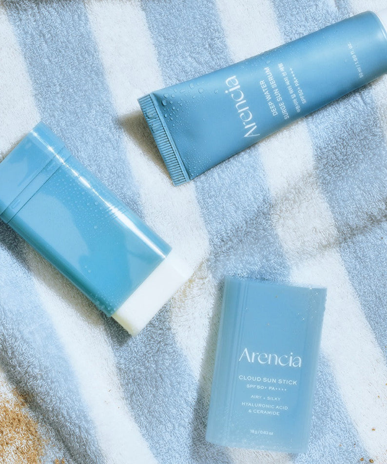 ARENCIA Cloud Sun Stick 18g sur une serviette, protection solaire compacte et hydratante, soin de la peau en voyage, SPF, look moderne.