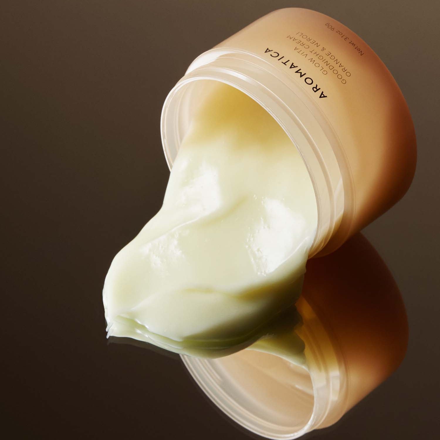 AROMATICA Glow Vita Good Night Cream Orange & Neroli 90G, pot de crème nuit sur fond brun, texture crème blanche.