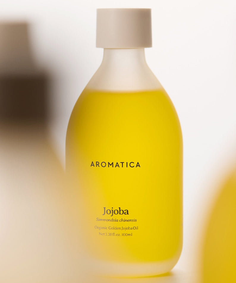 AROMATICA Organic Golden Jojoba Oil 100ml en flacon jaune, huile de jojoba bio, toile de fond floue, salle de bain spa