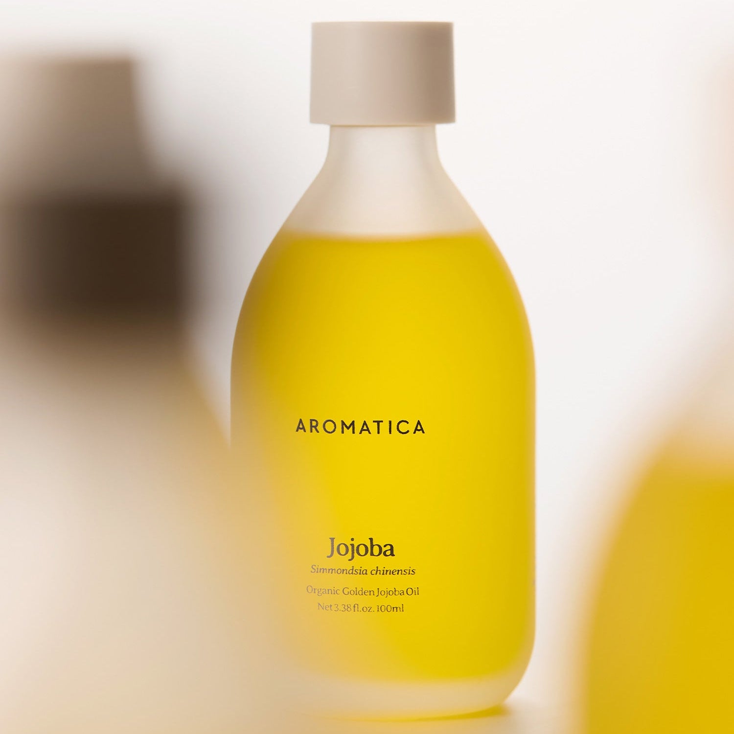 AROMATICA Organic Golden Jojoba Oil 100ml en flacon jaune, huile de jojoba bio, toile de fond floue, salle de bain spa