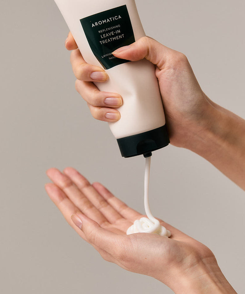 AROMATICA Replenishing Leave-In Treatment Lavender & Patchouli 150ML, crème sur mains, tube entre mains, fond beige