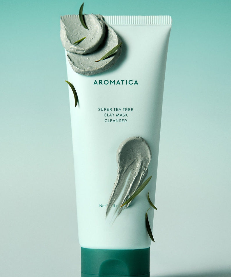 Décrivez l'image en français : AROMATICA Super Tea Tree Clay Mask Cleanser 150ML, tube vert sur fond bleu, feuilles de thé.