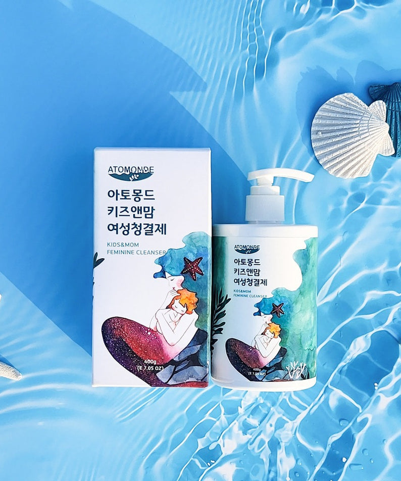 ATOMANDE Kids & Mom Feminine Cleanser 400g sur fond aquatique bleu, bouteille et étui, marque ATOMANDE, ambiance été.