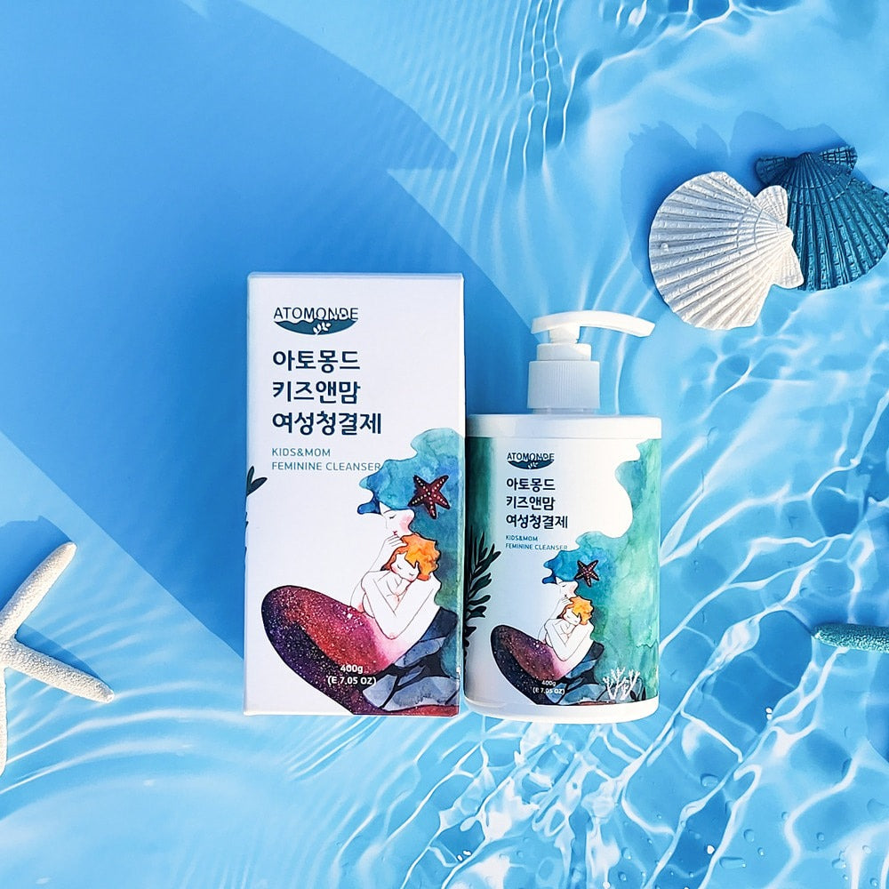 ATOMANDE Kids & Mom Feminine Cleanser 400g sur fond aquatique bleu, bouteille et étui, marque ATOMANDE, ambiance été.