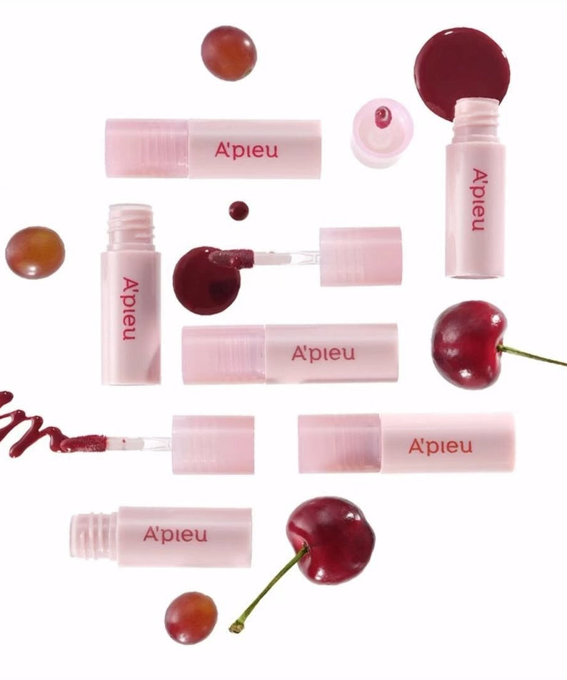 A'PIEU Juicy Pang Bear Cream Blusher Mini aligné avec des cerises, symbolisant la teinte juteuse et vive du produit cosmétique.