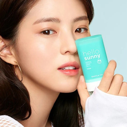 BANILA CO Hello Sunny Essence Sun Stick Fresh SPF50+PA++++, femme tenant le stick turquoise, protection solaire fraîche au quotidien.
