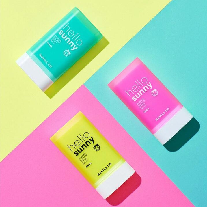 BANILA CO Hello Sunny Essence Sun Stick Fresh SPF50+PA++++, bâtons solaires en packaging coloré sur fond géométrique.