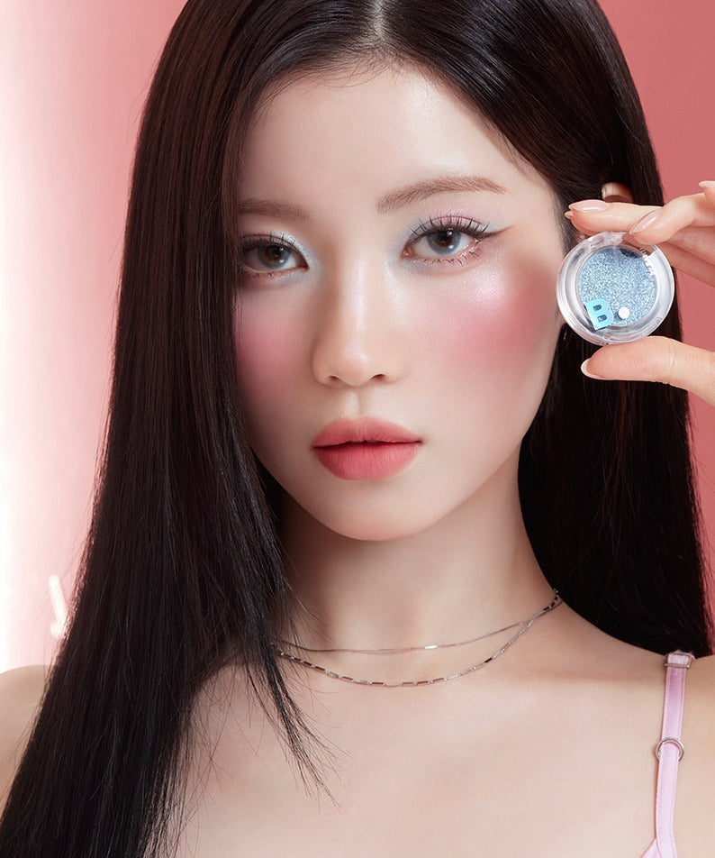 BANILA CO Hyper Holobeam Eye Glitter de la marque BANILACO, maquillage scintillant sur un œil, photo beauté sur fond rose.