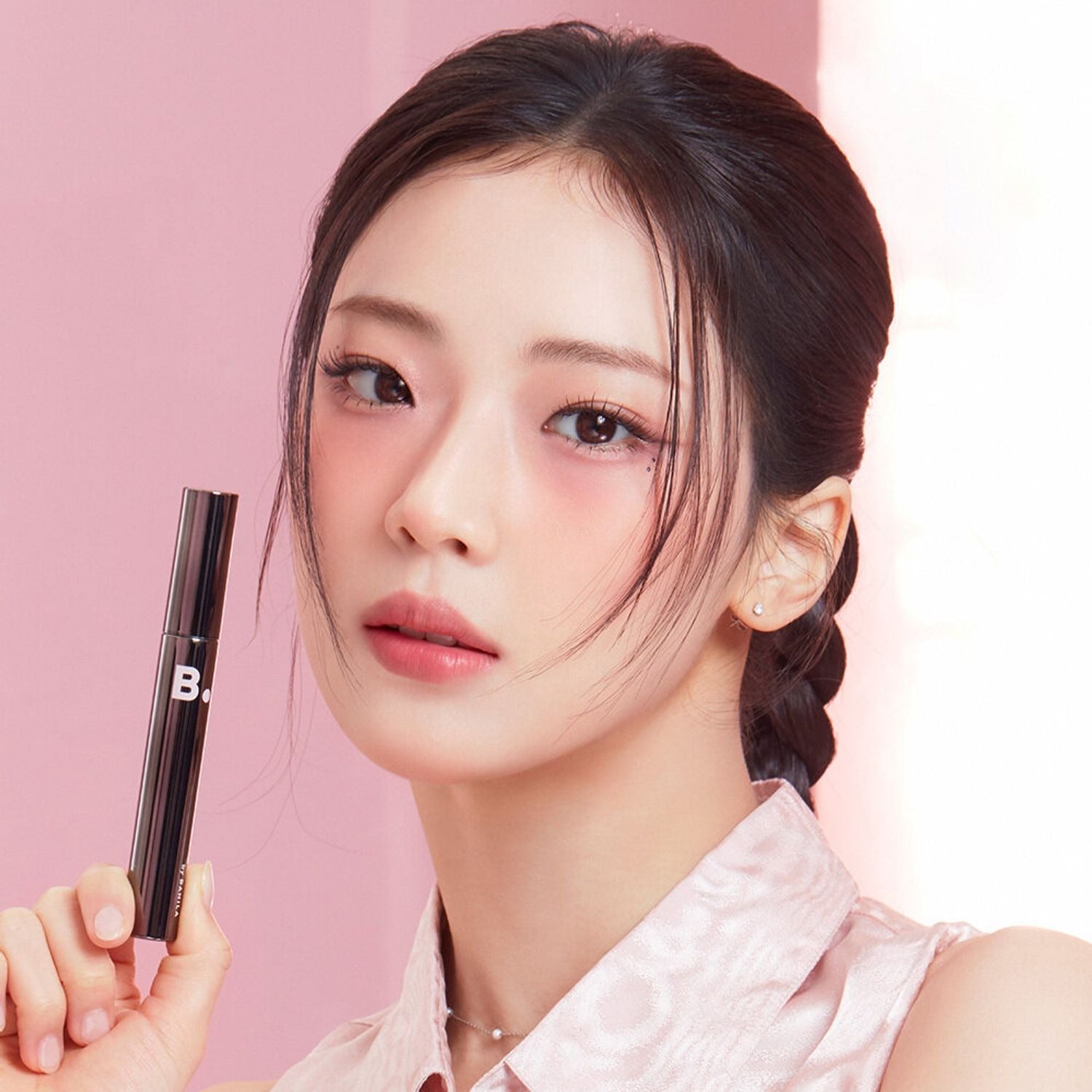 BANILA CO Powerproof Mascara de BANILACO, maquillage yeux sur fond rose, modèle en gros plan tenant le mascara.