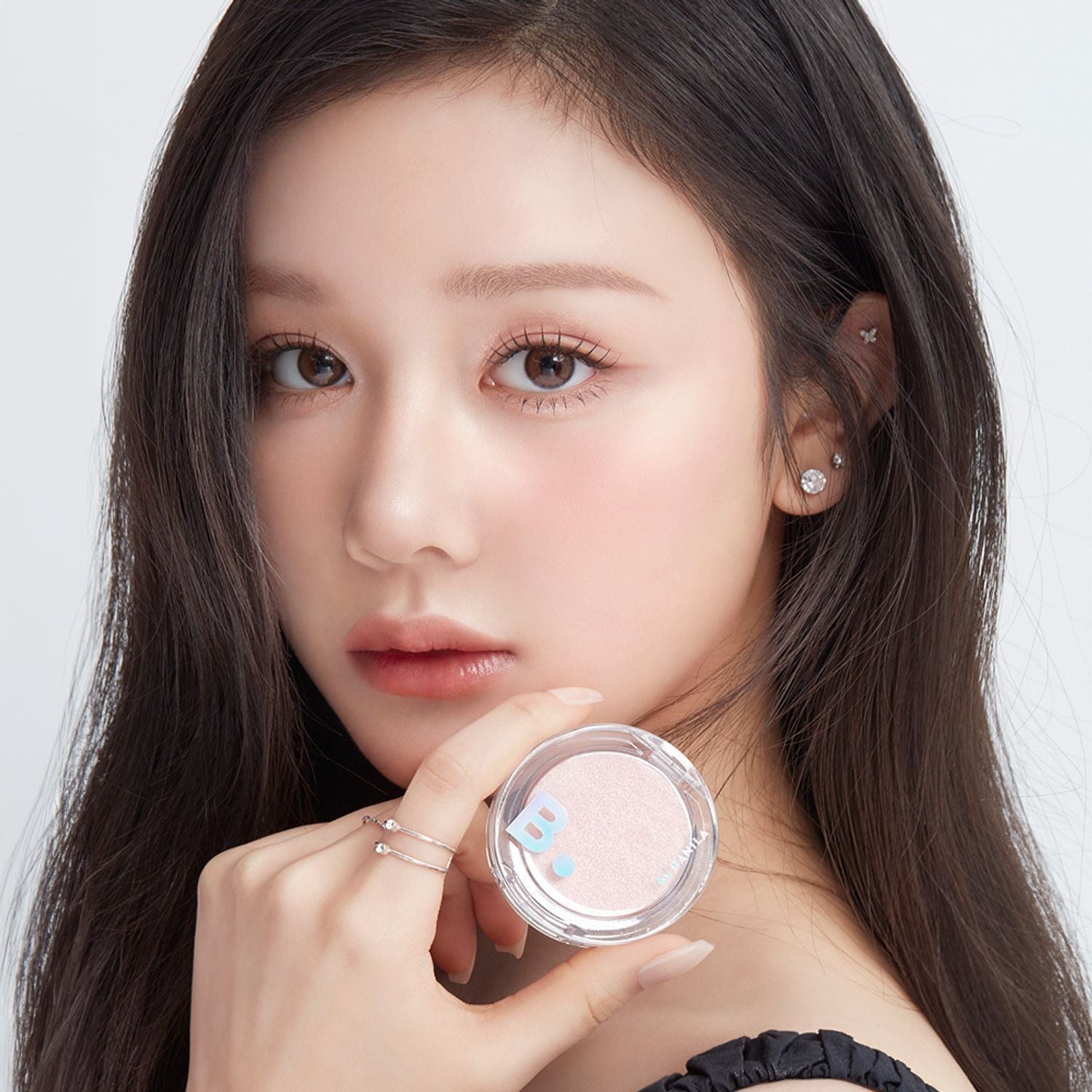 BANILA CO Silky Glow Highlighter, gros plan sur visage maquillé et poudre highlighter argentée, fond clair, marque Banila Co.