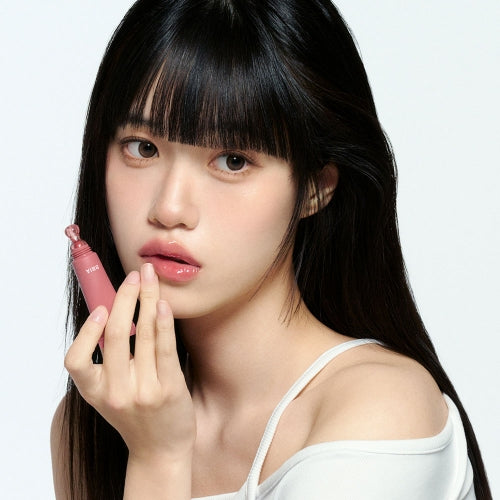 BBIA Lip Oil Essence de BBIA, sur lèvres hydratées, jeune femme au maquillage sur fond clair, produit en évidence.