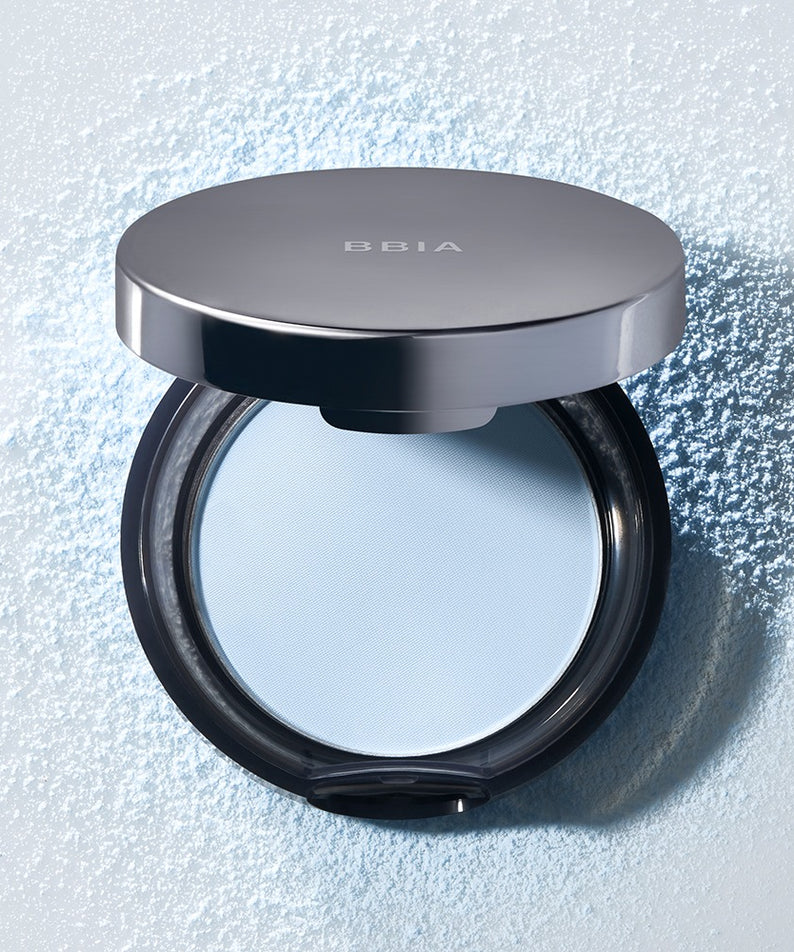 BBIA Oh Powder Pact de BBIA, poudre compacte posée sur fond lumineux avec particules d’éclat, visuel maquillage
