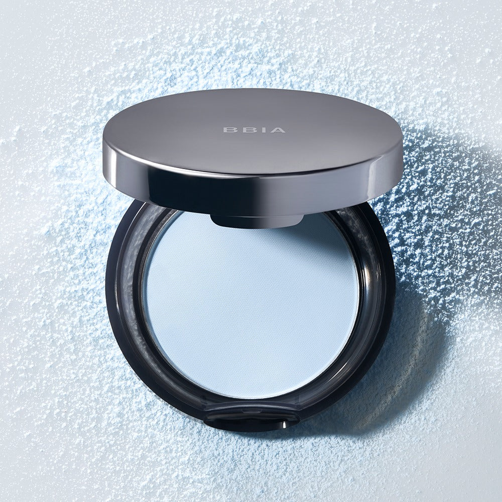 BBIA Oh Powder Pact de BBIA, poudre compacte posée sur fond lumineux avec particules d’éclat, visuel maquillage