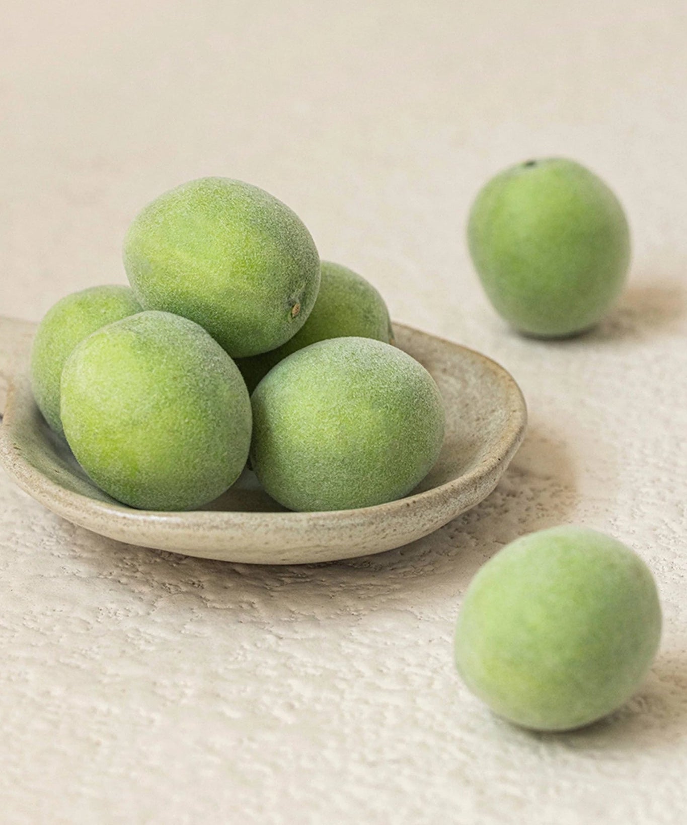Décris l'image en français: BEAUTY OF JOSEON Green Plum Refreshing Toner AHA + BHA 150ml, flacons sur bols de prunes vertes