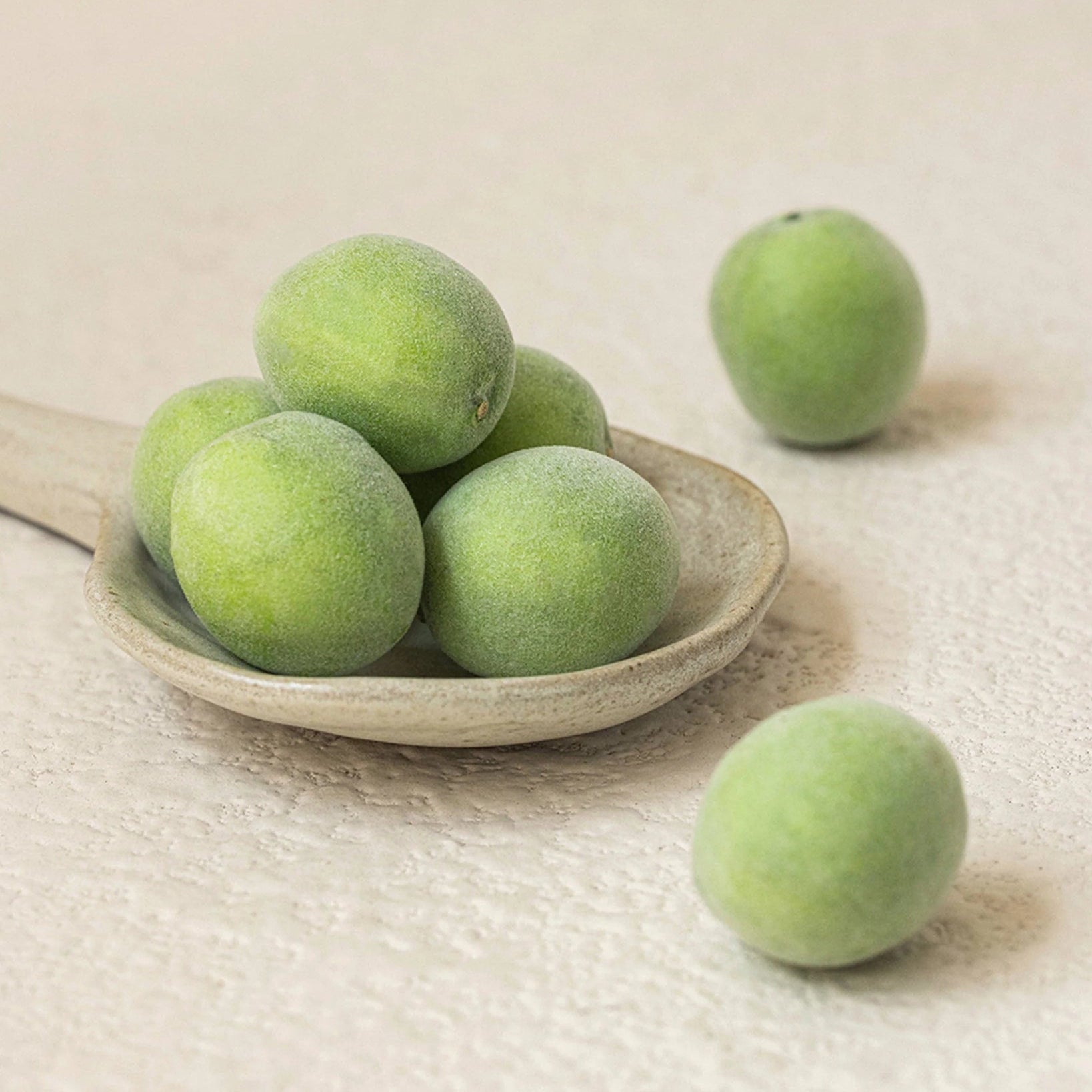 Décris l'image en français: BEAUTY OF JOSEON Green Plum Refreshing Toner AHA + BHA 150ml, flacons sur bols de prunes vertes