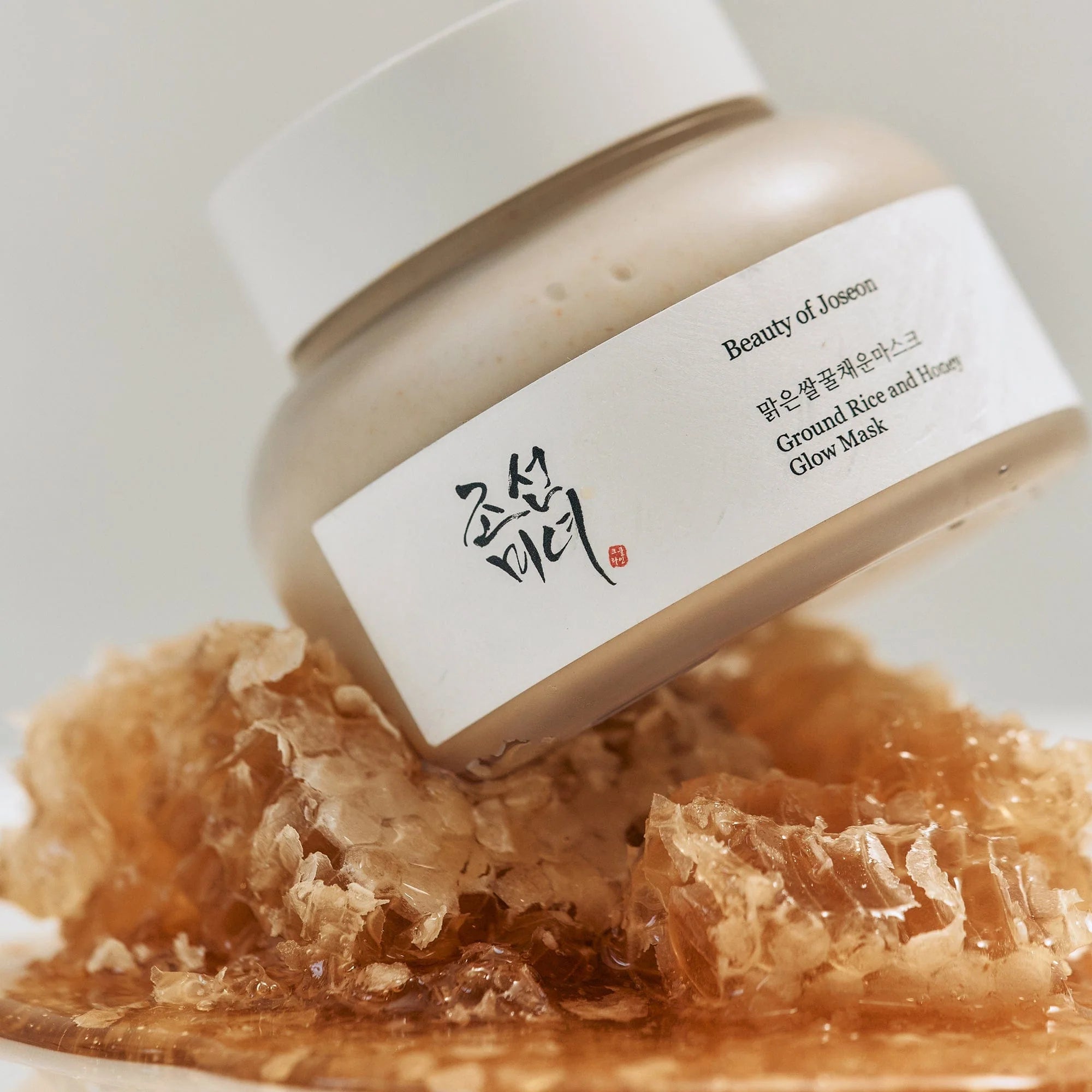 Décris l'image en français : BEAUTY OF JOSEON Ground Rice and Honey Glow Mask 150ml, pot et texture au miel.