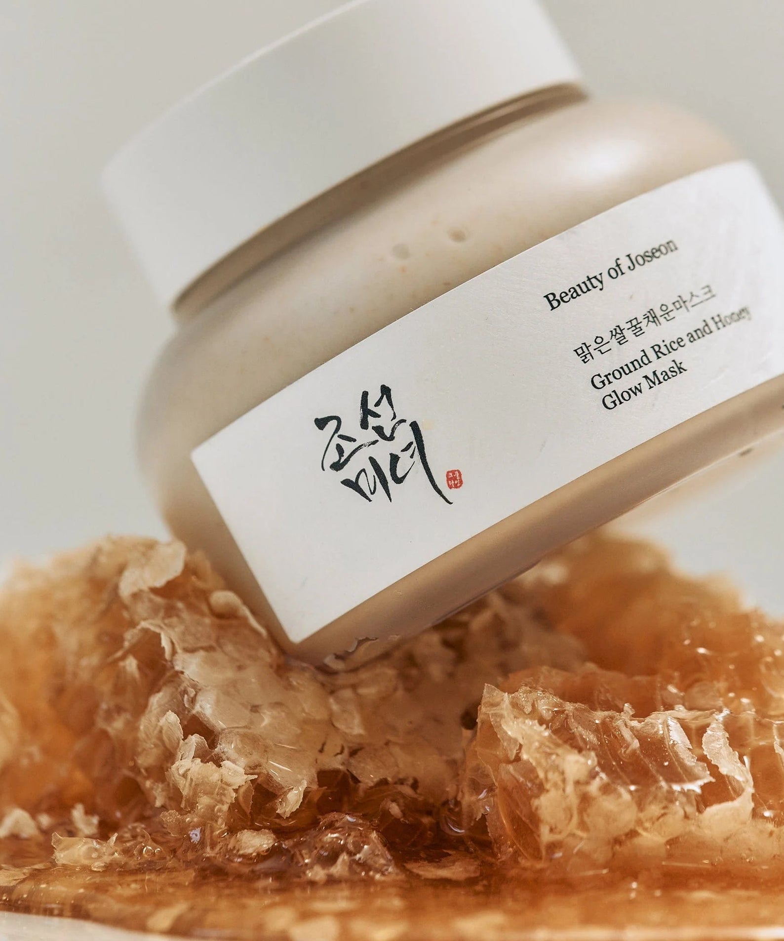Masque BEAUTY OF JOSEON Ground Rice and Honey Glow 150ml exposé sur un lit de miel doré, soin nourrissant pour un teint éclatant.